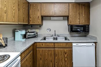 an empty kitchen with wooden cabinets and a sink and a stove